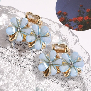 Close-up of golden flower hair claw clips with light blue petals and clear crystal centers
