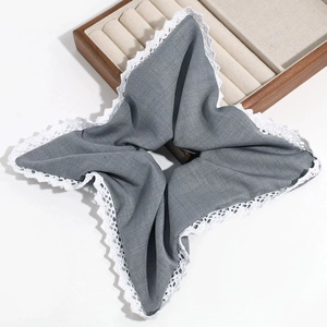 Detail of grey square fabric hair tie with white lace edges on a white background