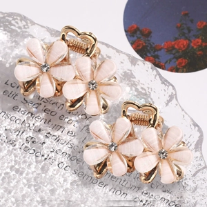Mini camellia hair claws with rhinestones and gold finish on elegant background
