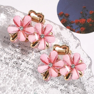 Close-up of pink camellia hair claws with gold-plated metal and sparkling rhinestones