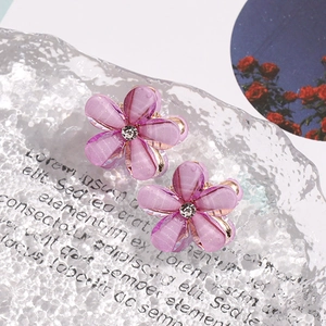 Close-up of translucent purple flower earrings with sparkling glitter and diamond center