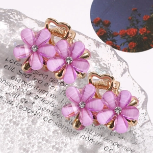 Detail of four mini purple flower hair claws with rhinestones and gold heart clips