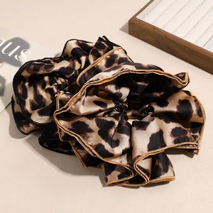 Chic leopard print oversized scrunchie made of glossy satin fabric on minimalist background