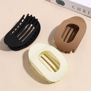 Trois pinces à cheveux mates en noir, marron et crème avec un design ovale minimaliste