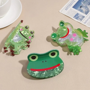 Drei süße grüne Frosch-Haarklammern aus Acryl mit Marmor-Textur auf schlichtem Hintergrund