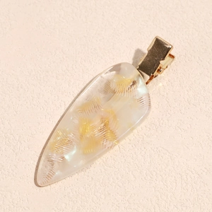 Macro shot of acetic acid hair clip with yellow feather patterns and gold metal base