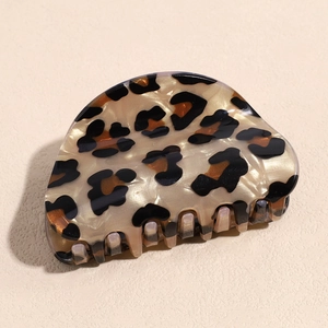 Macro detail of the leopard print hair claw clip showing acetate marble texture and teeth