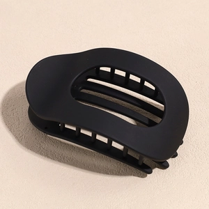 Détail d'une grande pince à cheveux creuse noir mat avec une texture givrée raffinée