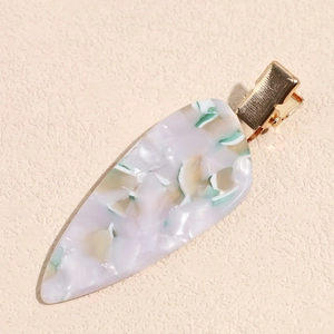 Detailed macro of teardrop acetate hair clip with purple marble pattern and gold metal grip