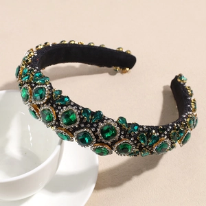 Detail view of deep green crystal rhinestones in vintage gold metal settings on a headband