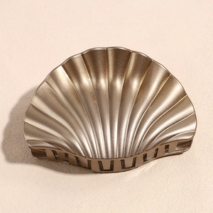 Detail view of champagne gold scallop hair claw with metallic pearl finish and smooth teeth