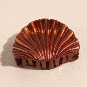 Detail view of red-brown shell hair claw with gold glitter finish and glossy resin texture