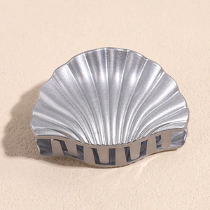 Detail of silver shell-shaped hair claw with matte metallic finish and precise teeth