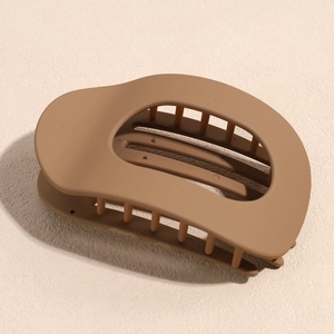 Gros plan sur la pince à cheveux marron mat avec dents solides sur surface beige