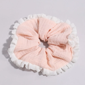 Detail of pink cotton linen scrunchie with white ruffled edges and pleated texture