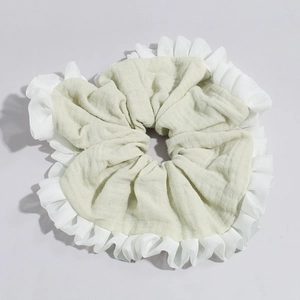 Close-up of light green linen scrunchie with white organza ruffled edges and layered texture