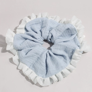 Close-up of light blue linen scrunchie with elegant white ruffled lace border details