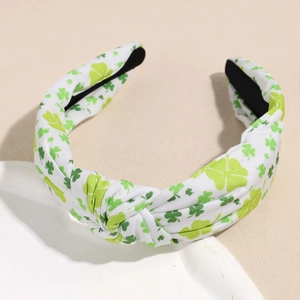 Gros plan détaillé d'un serre-tête noué large avec motifs de trèfle vert sur tissu blanc