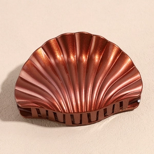 Detailed view of the shell-shaped bronze hair claw with a shimmering glitter finish