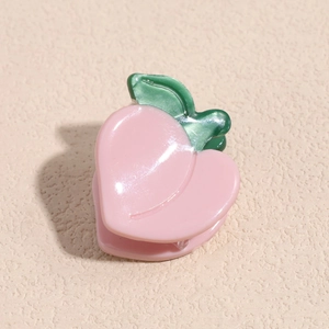 Macro view of peach shaped hair claw clip made of pink acetate with green leaves