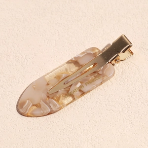 Macro detail of French retro acetate hair clip with marble pattern and gold metal