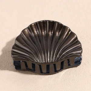 Close-up of shell-shaped hair claw clip with dark coffee color and golden glitter finish