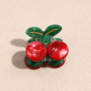 Detail of red cherry hair claw clip with green leaves and polished resin finish