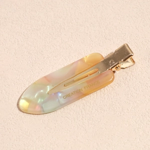 Macro shot of colorful acetate hair clip with Creation France engraving and gold metal
