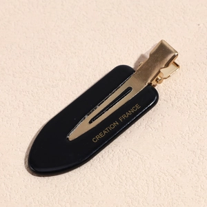 Close-up of a black acetate beak hair clip with gold metal clasp and French lettering