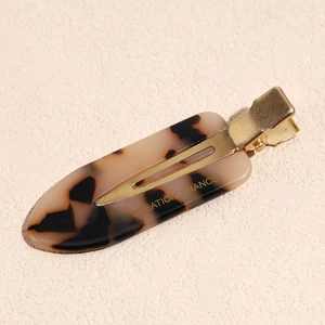 Detail of tortoiseshell acetate alligator hair clip with gold metal base and French text
