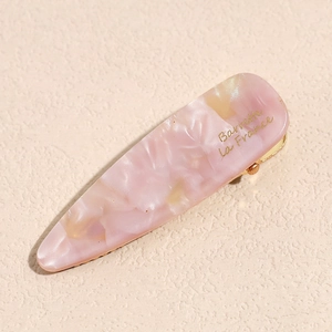Detail of pink marble acetate hair clip with golden metal base and French text