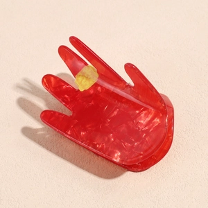 Macro detail of red translucent palm-shaped hair claw with marbled glitter texture