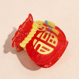 Close-up of red lucky bag hair claw clip with festive yellow cord and Fu character