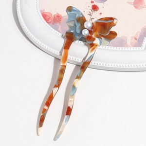 Detail of a butterfly acetate hair pin with marble texture and pearl accents