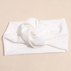 Dettaglio di una fascia in maglia a coste bianca con una rosa in tessuto 3D fatta a mano