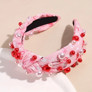 Detail eines rosa Stoffhaarbands mit LOVE-Print, roten Herzen und künstlichen Perlen