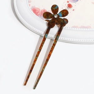 Macro detail of amber tortoiseshell hairpin with flower shape and crystal accent