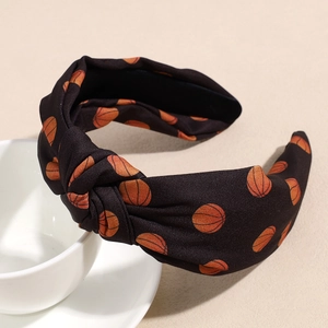 Détail d'un serre-tête noué noir avec imprimé basketball orange sur une tasse