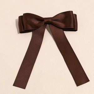 Detail of dark brown satin ribbon bow hair clip with elegant long hanging streamers