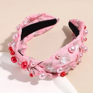 Detailaufnahme rosa Haarreif mit Knotendesign, Bärenmuster und glänzenden Perlen