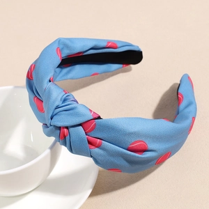 Détail d'un serre-tête en tissu bleu avec motif tennis sur une tasse de café