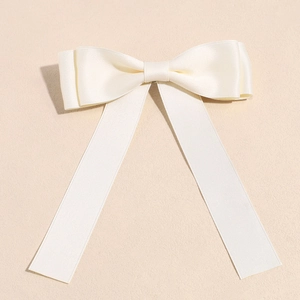 Detail view of cream white satin ribbon bow clip with elegant silky texture