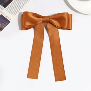 Detailed flat lay of caramel satin ribbon hair clip with elegant long streamers