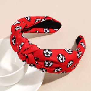 Détail d'un serre-tête noué rouge à motif de football posé sur une tasse blanche