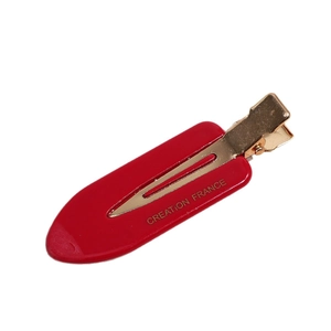 Red acetate beak hair clip with gold metal spring and Creation France text on white background