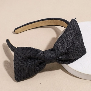 Gedetailleerde close-up van een zwarte raffia hoofdband met strik en geweven textuur