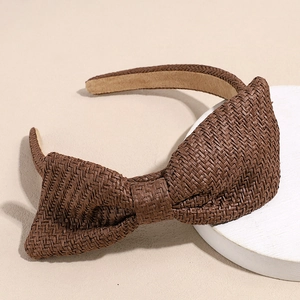 Detail van de gevlochten raffia textuur en antislip voering van de bruine strik haarband
