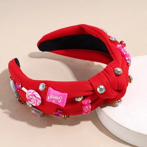 Detail eines roten Knotenstirnbands mit bunten Strasssteinen und süßem Bonbon-Dekor