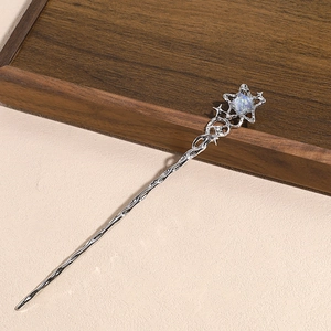 Close-up of a silver star hair pin with iridescent gem and spiral texture