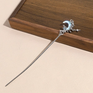 Detail view of silver hair stick with moon star design and blue shell inlay on dark wood